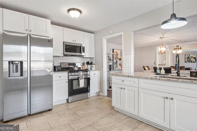 kitchen featuring decorative light fixtures, white cabinetry, and stainless steel appliances