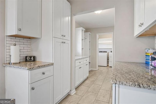 kitchen with independent washer and dryer, white cabinets, decorative backsplash, and light stone countertops