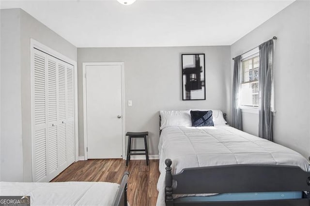 bedroom with dark wood-type flooring and a closet