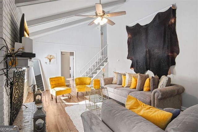 living room with a fireplace, light wood-type flooring, lofted ceiling with beams, and ceiling fan