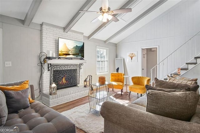 living room with hardwood / wood-style flooring, a brick fireplace, ceiling fan, and vaulted ceiling with beams