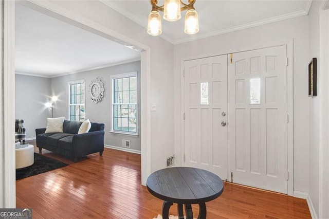 foyer featuring a notable chandelier, hardwood / wood-style flooring, and crown molding