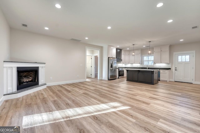 kitchen featuring pendant lighting, tasteful backsplash, a center island, light hardwood / wood-style floors, and stainless steel appliances