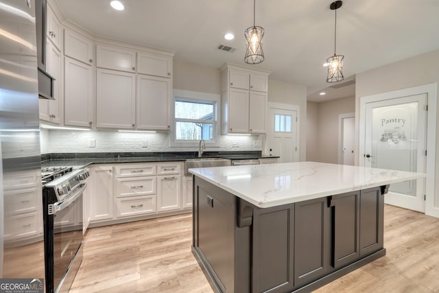 kitchen with decorative light fixtures, white cabinets, a center island, and appliances with stainless steel finishes