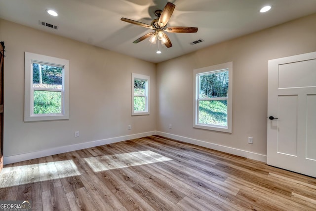 unfurnished room with ceiling fan, a wealth of natural light, and light wood-type flooring