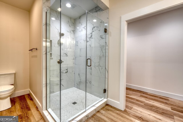 bathroom with wood-type flooring, toilet, and an enclosed shower