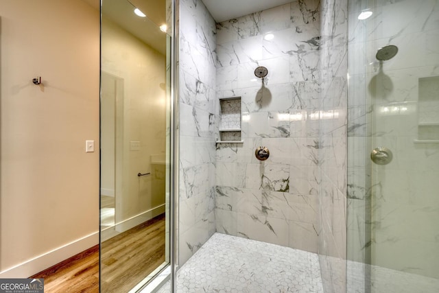 bathroom with hardwood / wood-style floors and a tile shower