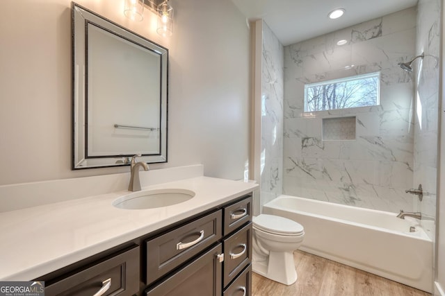 full bathroom with hardwood / wood-style flooring, toilet, vanity, and tiled shower / bath