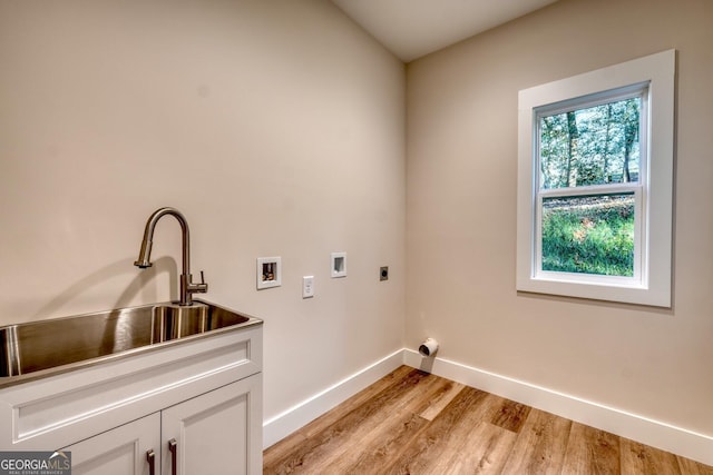 laundry area with light wood-type flooring, cabinets, sink, hookup for a washing machine, and hookup for an electric dryer