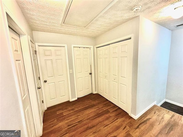 corridor with a textured ceiling and dark hardwood / wood-style flooring