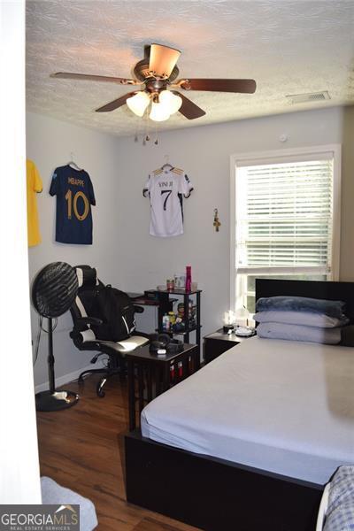 bedroom featuring ceiling fan, a textured ceiling, and dark hardwood / wood-style flooring