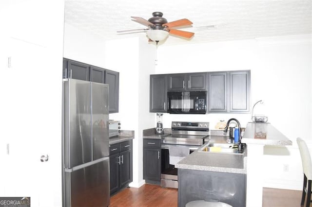 kitchen with ceiling fan, a textured ceiling, sink, stainless steel appliances, and dark hardwood / wood-style floors