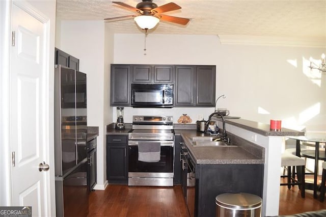 kitchen with ceiling fan, a textured ceiling, sink, stainless steel appliances, and dark hardwood / wood-style floors