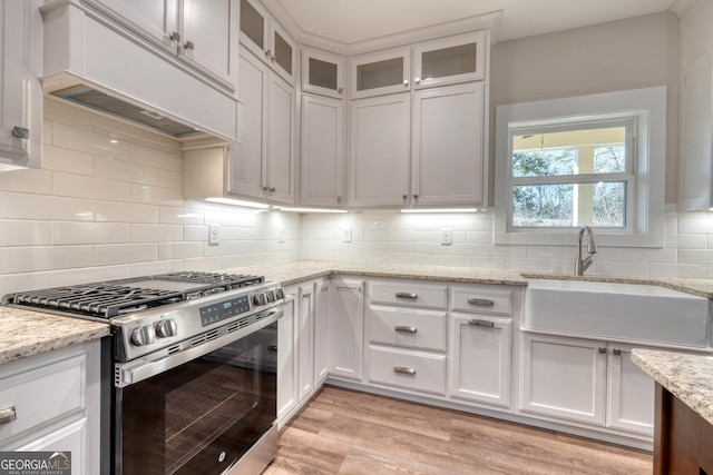 kitchen featuring white cabinetry, custom range hood, and gas stove