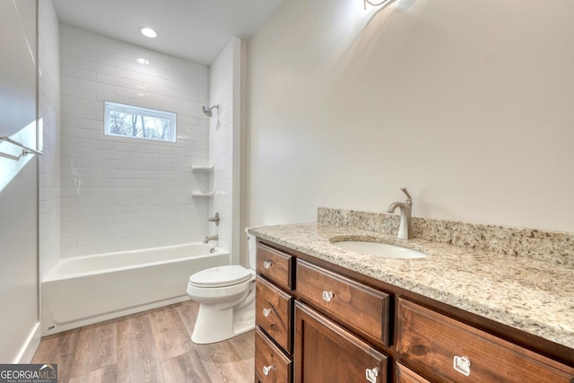 full bathroom featuring vanity, hardwood / wood-style flooring, tiled shower / bath, and toilet