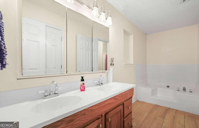 bathroom featuring a tub to relax in, wood-type flooring, a textured ceiling, and vanity