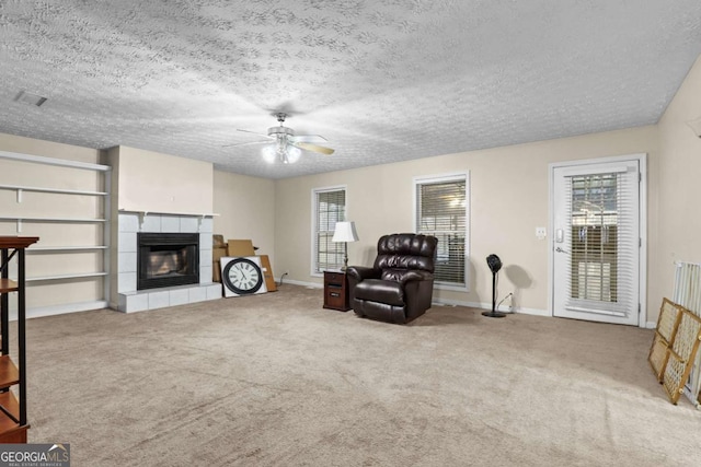 living area with a tiled fireplace, a wealth of natural light, and a textured ceiling