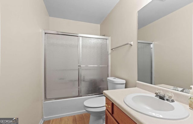 full bathroom with wood-type flooring, toilet, combined bath / shower with glass door, and vanity