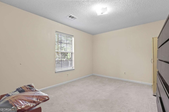 carpeted empty room featuring a textured ceiling