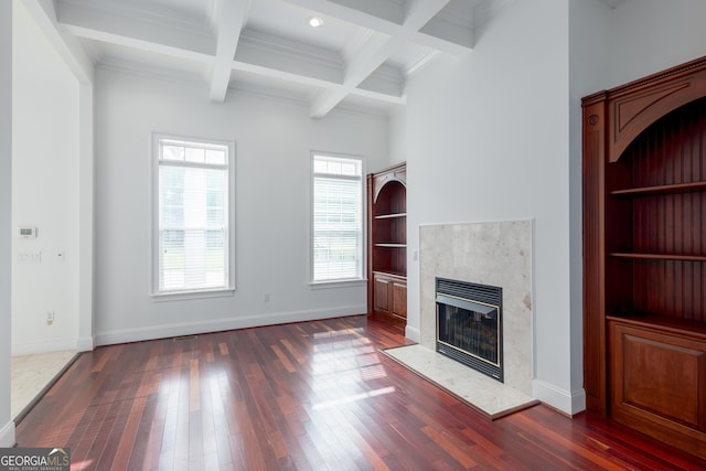 unfurnished living room featuring dark hardwood / wood-style flooring, a fireplace, ornamental molding, beam ceiling, and coffered ceiling