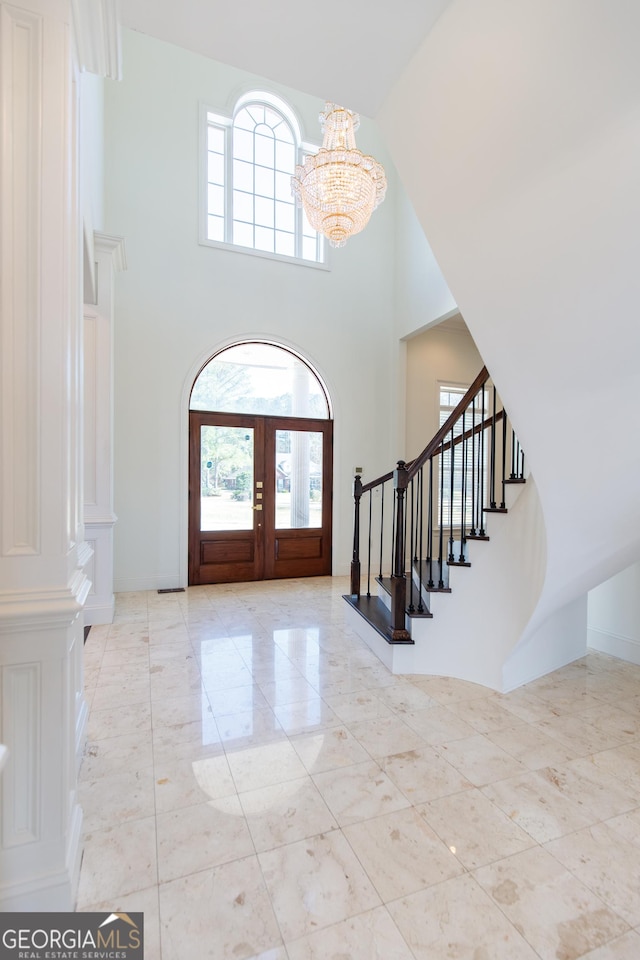 foyer with a high ceiling, french doors, and an inviting chandelier