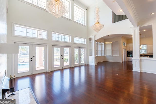 unfurnished living room featuring ornate columns, a wealth of natural light, and french doors