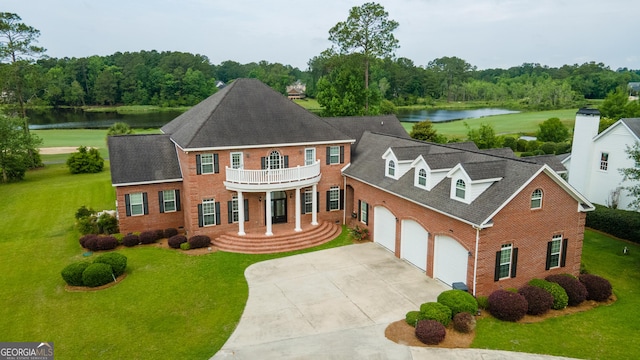 colonial-style house with a water view, a balcony, a front yard, and a garage