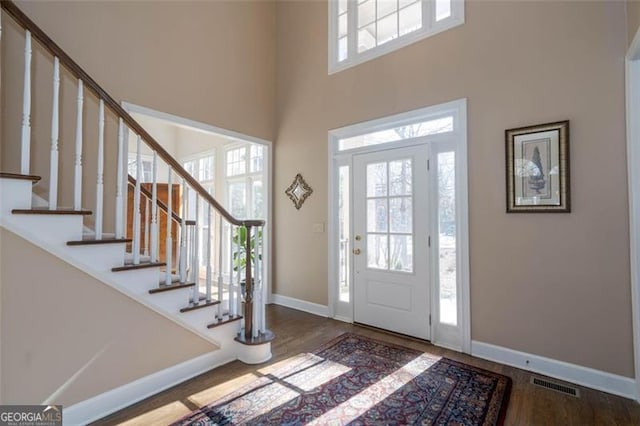 entryway featuring hardwood / wood-style flooring and a towering ceiling