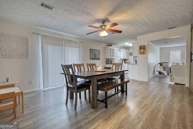 dining room featuring hardwood / wood-style flooring, ceiling fan, and a textured ceiling