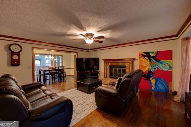 living room with a notable chandelier, a brick fireplace, hardwood / wood-style floors, and a textured ceiling