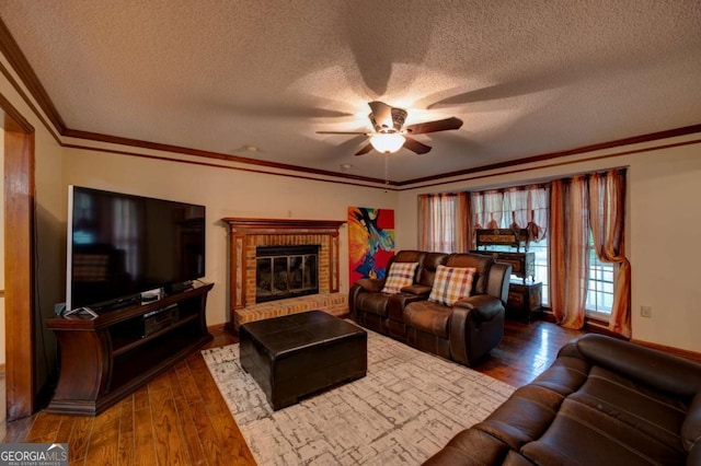 living room featuring crown molding, a fireplace, a textured ceiling, dark wood-type flooring, and ceiling fan