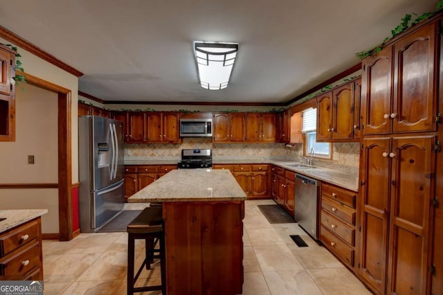 kitchen with a kitchen bar, light stone countertops, appliances with stainless steel finishes, a kitchen island, and ornamental molding