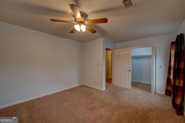 unfurnished bedroom with ceiling fan, light colored carpet, a textured ceiling, and a closet