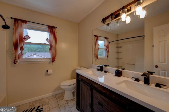 bathroom featuring toilet, a shower, a wealth of natural light, and vanity