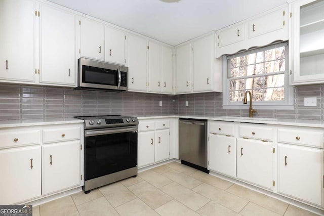 kitchen with a sink, appliances with stainless steel finishes, backsplash, and light countertops