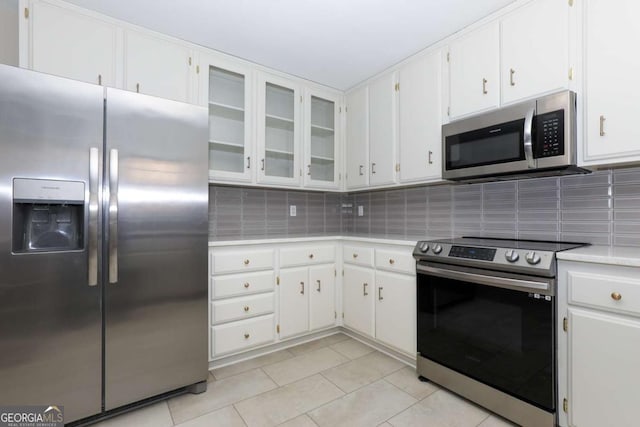 kitchen featuring light tile patterned flooring, light countertops, white cabinets, tasteful backsplash, and stainless steel appliances