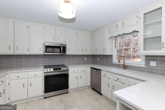 kitchen with light countertops, stainless steel appliances, white cabinets, and a sink