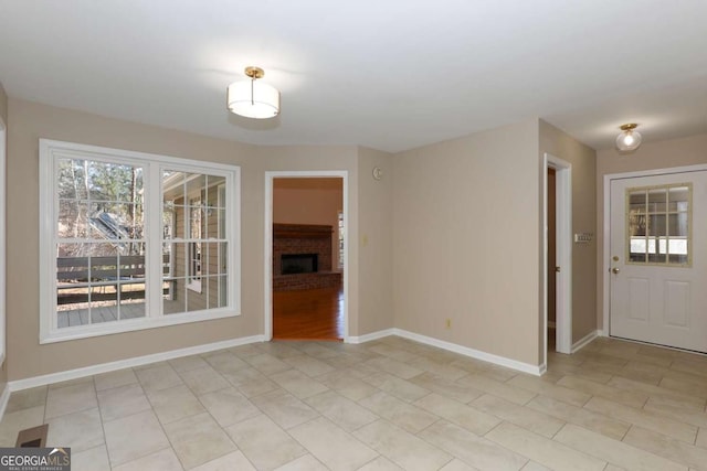 unfurnished dining area featuring baseboards, a brick fireplace, and light tile patterned flooring