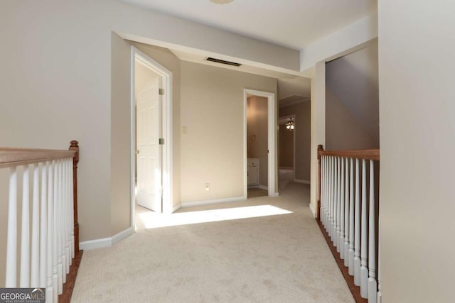 hallway featuring carpet floors, baseboards, and visible vents