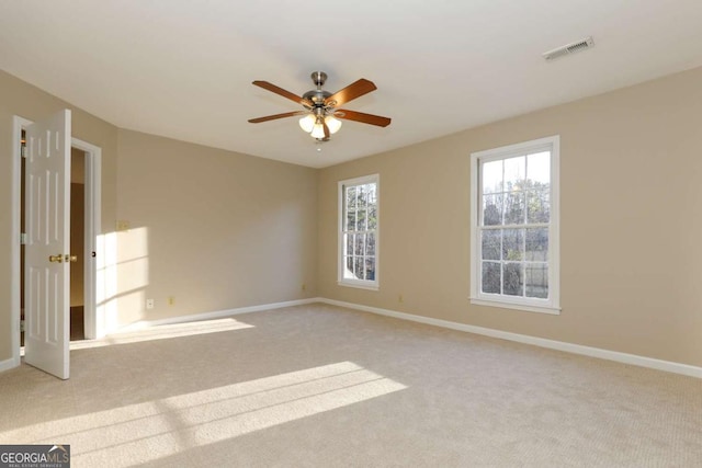 carpeted spare room featuring a ceiling fan, baseboards, and visible vents