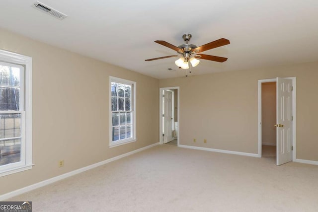 spare room with ceiling fan, visible vents, light carpet, and baseboards