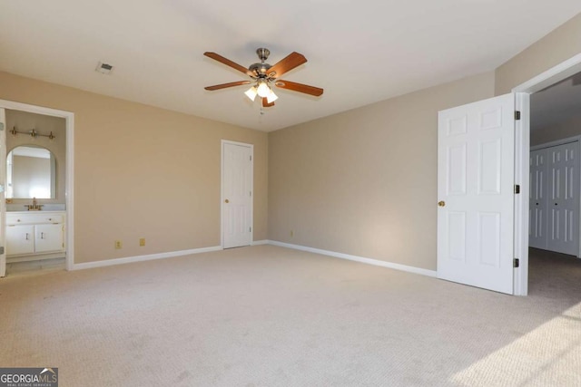 unfurnished bedroom with ceiling fan, light carpet, ensuite bath, baseboards, and visible vents