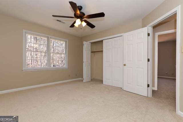 unfurnished bedroom with visible vents, a closet, baseboards, ceiling fan, and light colored carpet