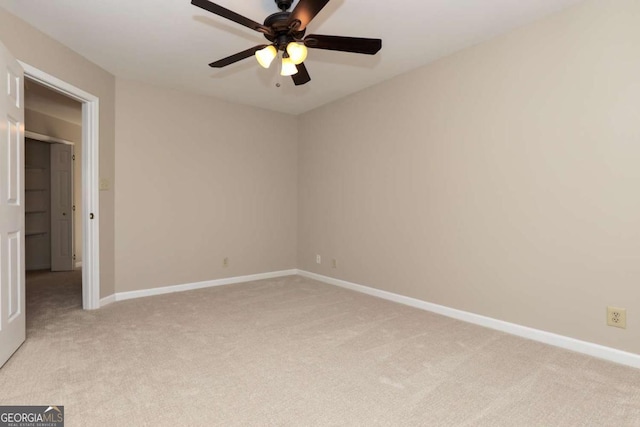 spare room featuring baseboards, light carpet, and a ceiling fan