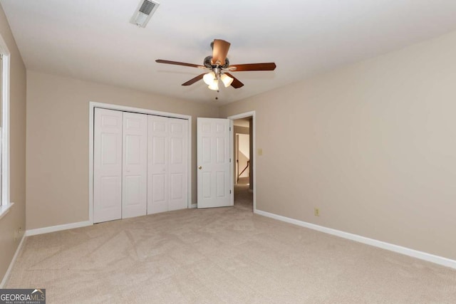 unfurnished bedroom with light carpet, a closet, and ceiling fan