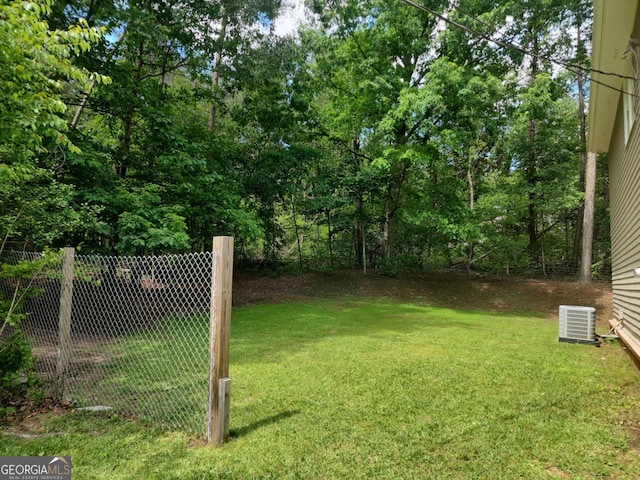 view of yard featuring central AC and fence