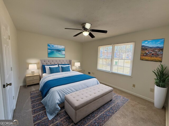 bedroom with a textured ceiling, light colored carpet, and ceiling fan