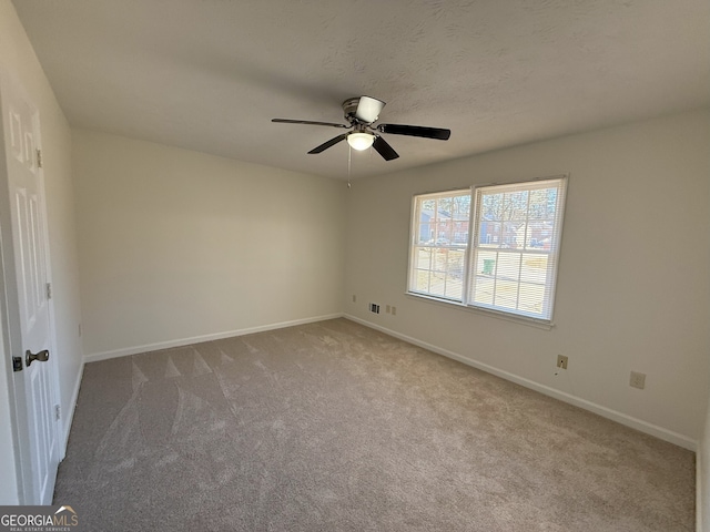 carpeted spare room featuring ceiling fan and a textured ceiling