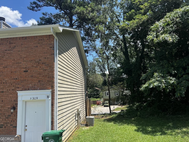 view of side of home featuring central AC and a lawn