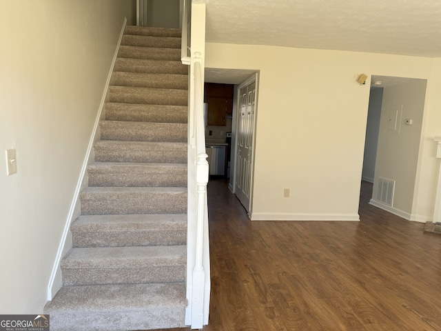 staircase with hardwood / wood-style floors and a textured ceiling